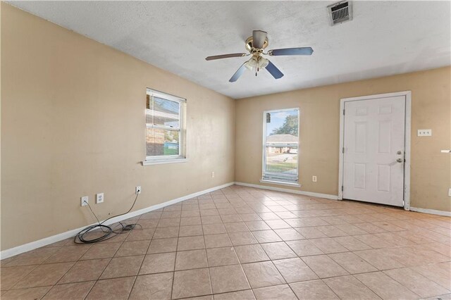 tiled spare room with a textured ceiling and ceiling fan