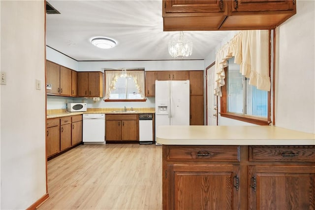 kitchen featuring an inviting chandelier, white electric stovetop, light wood-type flooring, double oven, and decorative light fixtures