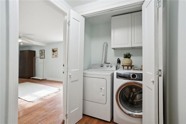 clothes washing area with cabinets, independent washer and dryer, light hardwood / wood-style floors, and ceiling fan