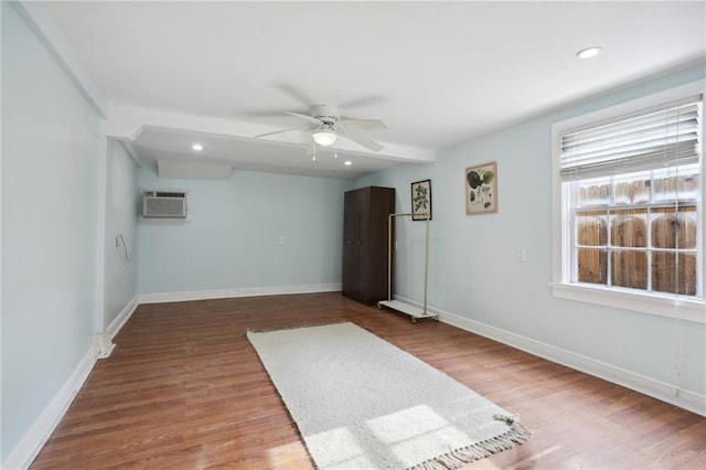 empty room with hardwood / wood-style flooring, an AC wall unit, and ceiling fan