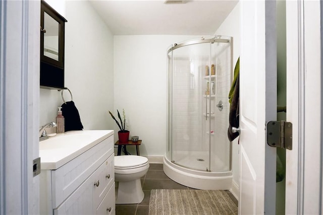 bathroom with tile patterned flooring, vanity, toilet, and a shower with shower door