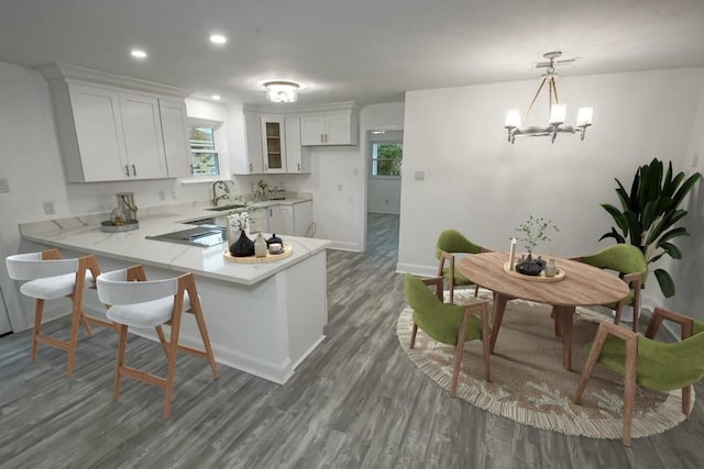 kitchen with kitchen peninsula, dark hardwood / wood-style floors, hanging light fixtures, a notable chandelier, and white cabinets