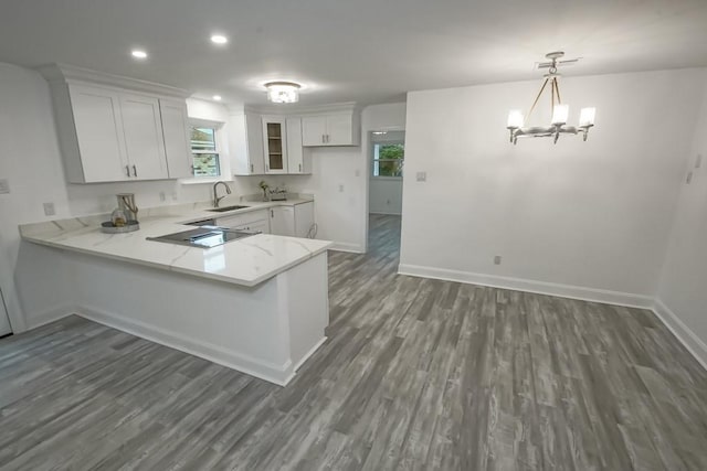 kitchen featuring dark hardwood / wood-style flooring, white cabinets, kitchen peninsula, sink, and pendant lighting