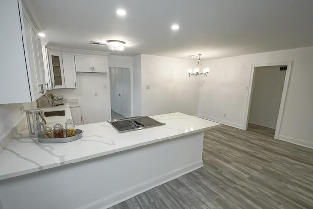 kitchen featuring white cabinetry, kitchen peninsula, dark hardwood / wood-style floors, hanging light fixtures, and a notable chandelier