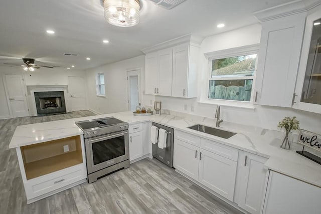 kitchen featuring stainless steel appliances, white cabinets, kitchen peninsula, sink, and light stone countertops