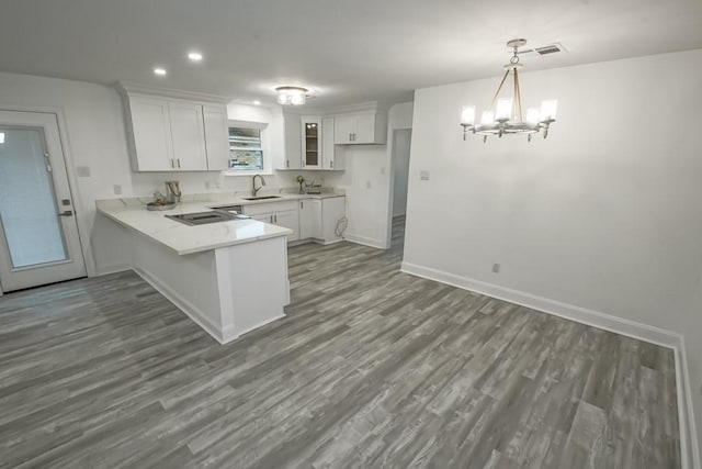 kitchen featuring sink, kitchen peninsula, decorative light fixtures, white cabinets, and dark wood-type flooring