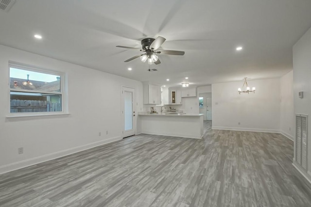 unfurnished living room with hardwood / wood-style flooring and ceiling fan with notable chandelier