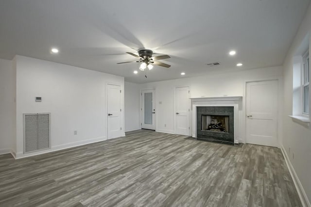 unfurnished living room with hardwood / wood-style flooring, a tiled fireplace, and ceiling fan