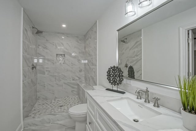 bathroom featuring vanity, toilet, and tiled shower