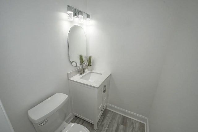 bathroom with toilet, vanity, and hardwood / wood-style floors