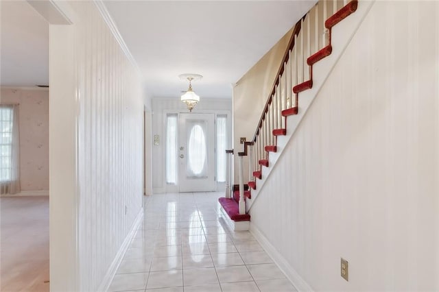 foyer with light tile patterned floors and ornamental molding