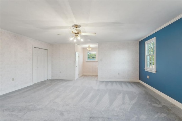 carpeted spare room featuring ceiling fan and crown molding