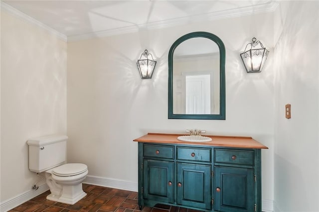 bathroom with toilet, vanity, and crown molding