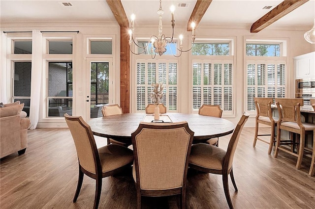 dining room with light hardwood / wood-style floors, a chandelier, beamed ceiling, and ornamental molding