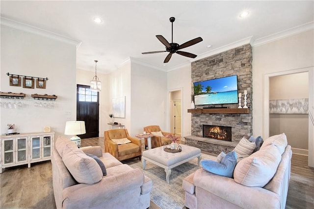 living room with wood-type flooring, a fireplace, ceiling fan, and ornamental molding