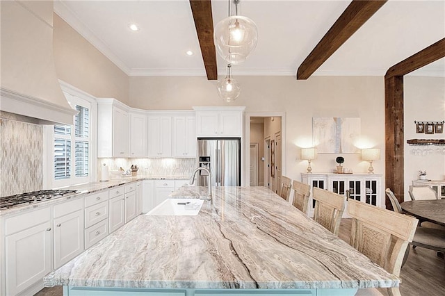 kitchen with sink, stainless steel appliances, decorative backsplash, and a spacious island