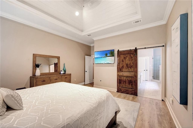 bedroom with a tray ceiling, a barn door, light hardwood / wood-style flooring, and crown molding