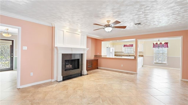 unfurnished living room featuring visible vents, ornamental molding, baseboards, a fireplace, and ceiling fan with notable chandelier