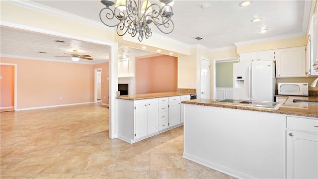 kitchen with ceiling fan with notable chandelier, ornamental molding, white appliances, a peninsula, and white cabinetry