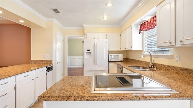 kitchen featuring white cabinets, a peninsula, a sink, white appliances, and ornamental molding