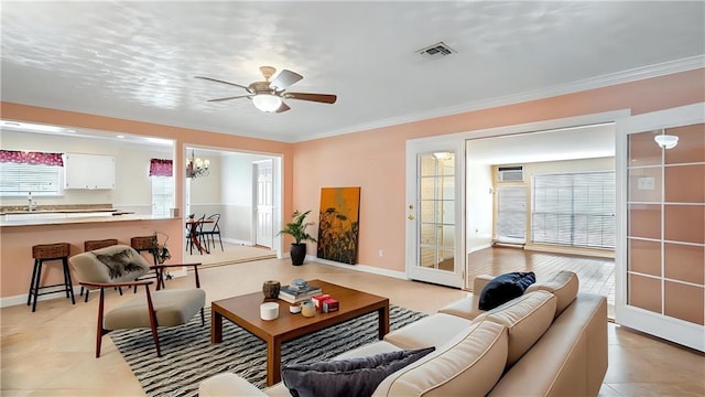 living area featuring visible vents, a ceiling fan, ornamental molding, light tile patterned floors, and baseboards