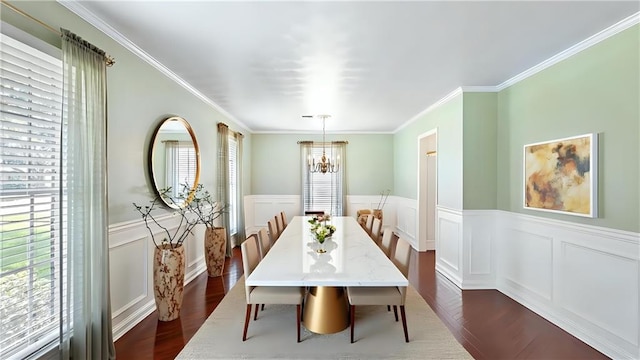 dining room featuring dark wood finished floors, a wainscoted wall, a decorative wall, crown molding, and a notable chandelier
