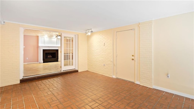 unfurnished living room with a fireplace, ceiling fan, brick patterned floor, and brick wall