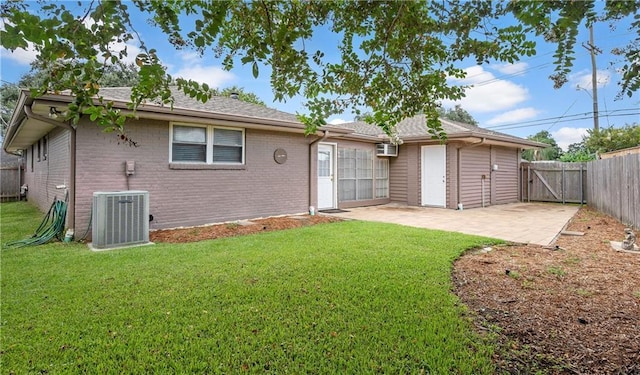 back of house featuring central AC unit, a fenced backyard, a patio area, a lawn, and brick siding