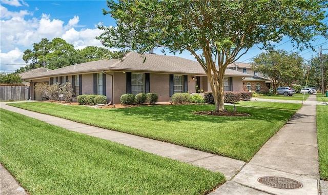 single story home featuring an attached garage, brick siding, fence, and a front yard