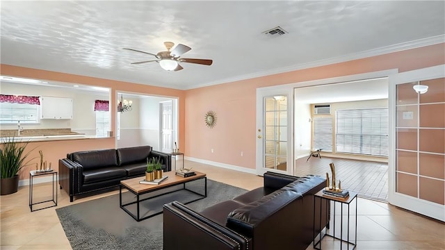 living room with visible vents, ornamental molding, light tile patterned floors, baseboards, and ceiling fan