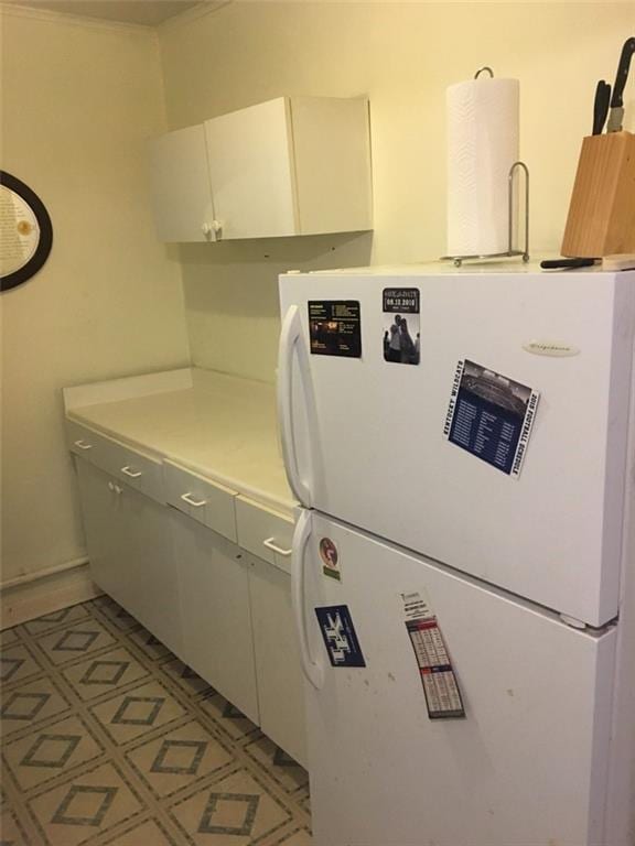 kitchen featuring white cabinets and white fridge