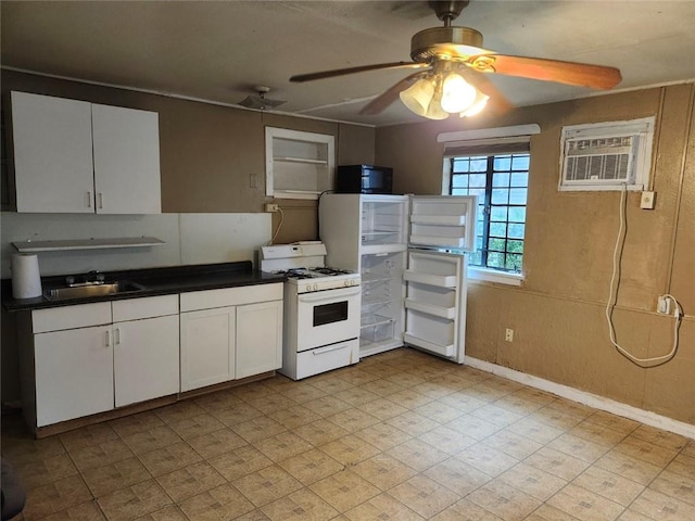 kitchen with an AC wall unit, white cabinetry, gas range gas stove, and sink