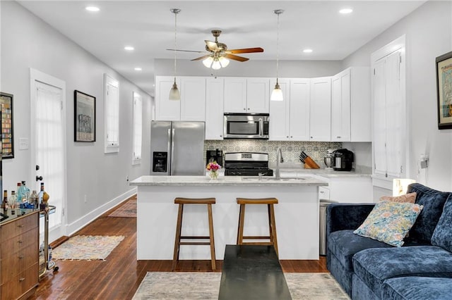 kitchen with pendant lighting, white cabinetry, appliances with stainless steel finishes, and tasteful backsplash