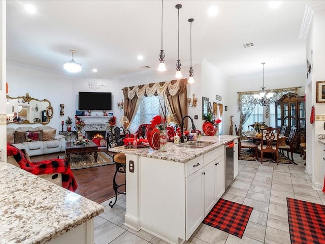 kitchen featuring hanging light fixtures, white cabinetry, a kitchen island with sink, and sink