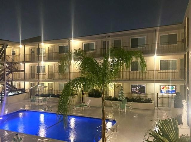 pool at night featuring a patio