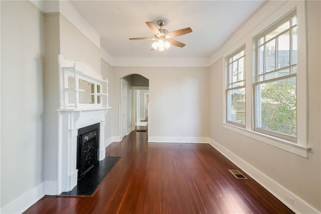 unfurnished living room featuring a wealth of natural light, dark wood-type flooring, and ceiling fan