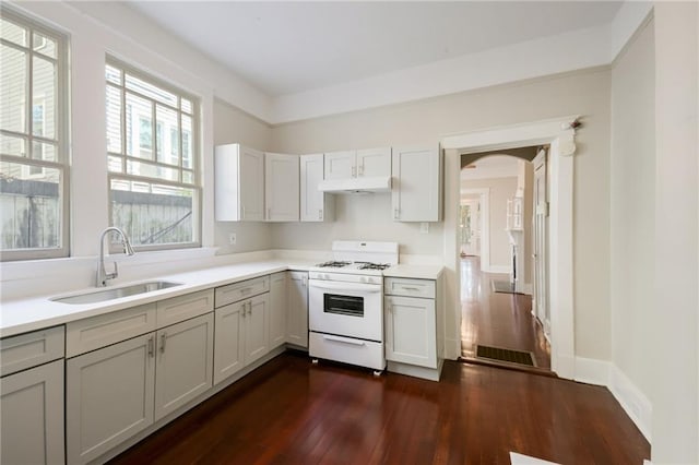 kitchen with dark hardwood / wood-style flooring, white cabinetry, white gas stove, and sink