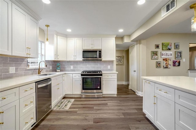 kitchen with sink, stainless steel appliances, hanging light fixtures, and light hardwood / wood-style flooring