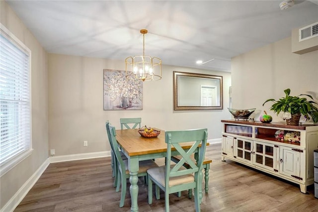 dining space with hardwood / wood-style flooring and a chandelier