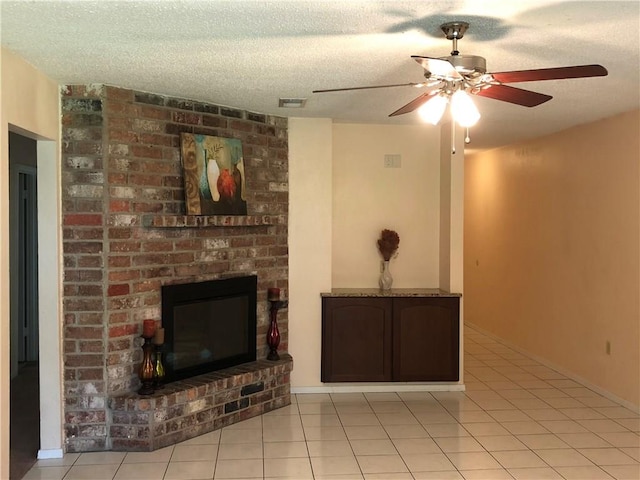 unfurnished living room featuring a fireplace, ceiling fan, light tile patterned flooring, and a textured ceiling