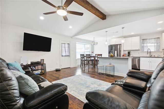 living room featuring a wealth of natural light, lofted ceiling with beams, sink, and dark wood-type flooring