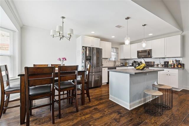 kitchen featuring white cabinetry, hanging light fixtures, appliances with stainless steel finishes, and dark wood-type flooring