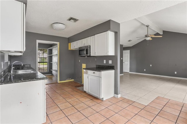 kitchen with white cabinetry, sink, ceiling fan, lofted ceiling with beams, and a textured ceiling