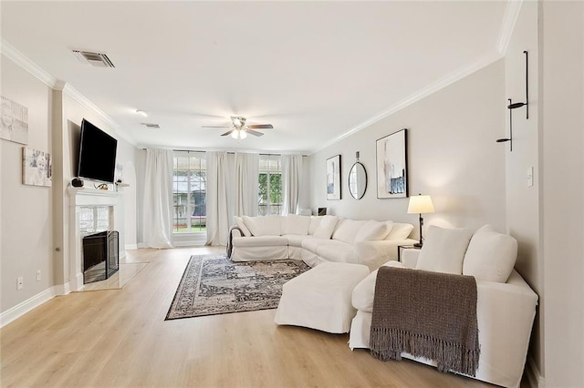 living room with crown molding, light wood-type flooring, and ceiling fan