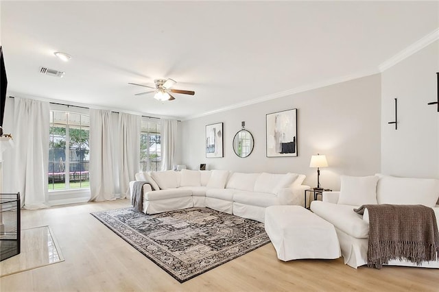 living room featuring light hardwood / wood-style floors, ceiling fan, and ornamental molding