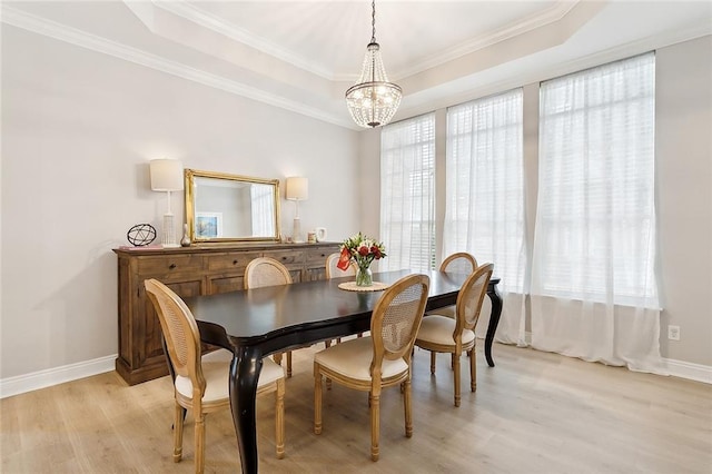 dining space with light wood-type flooring, a wealth of natural light, and a tray ceiling