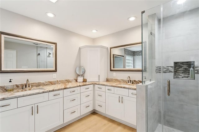 bathroom with a shower with door, hardwood / wood-style floors, and vanity