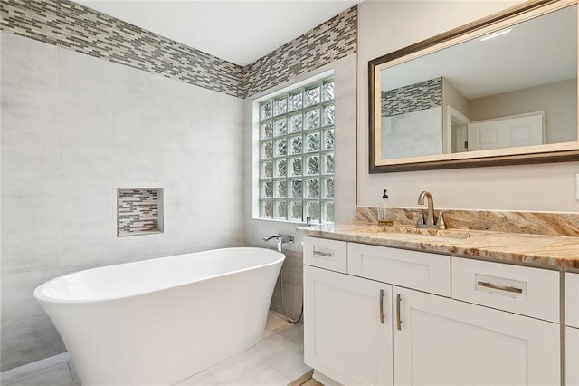 bathroom featuring a bathtub, vanity, and tile walls