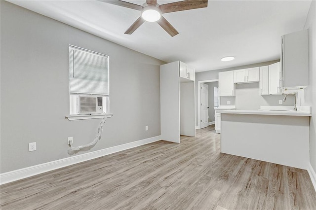 kitchen featuring cooling unit, light hardwood / wood-style flooring, white cabinets, and sink