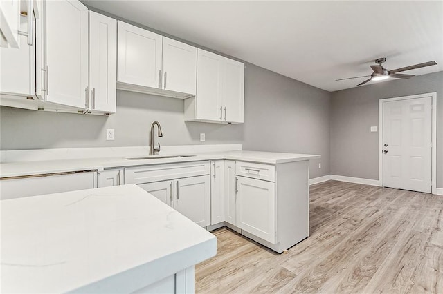 kitchen with ceiling fan, sink, white cabinets, and light wood-type flooring